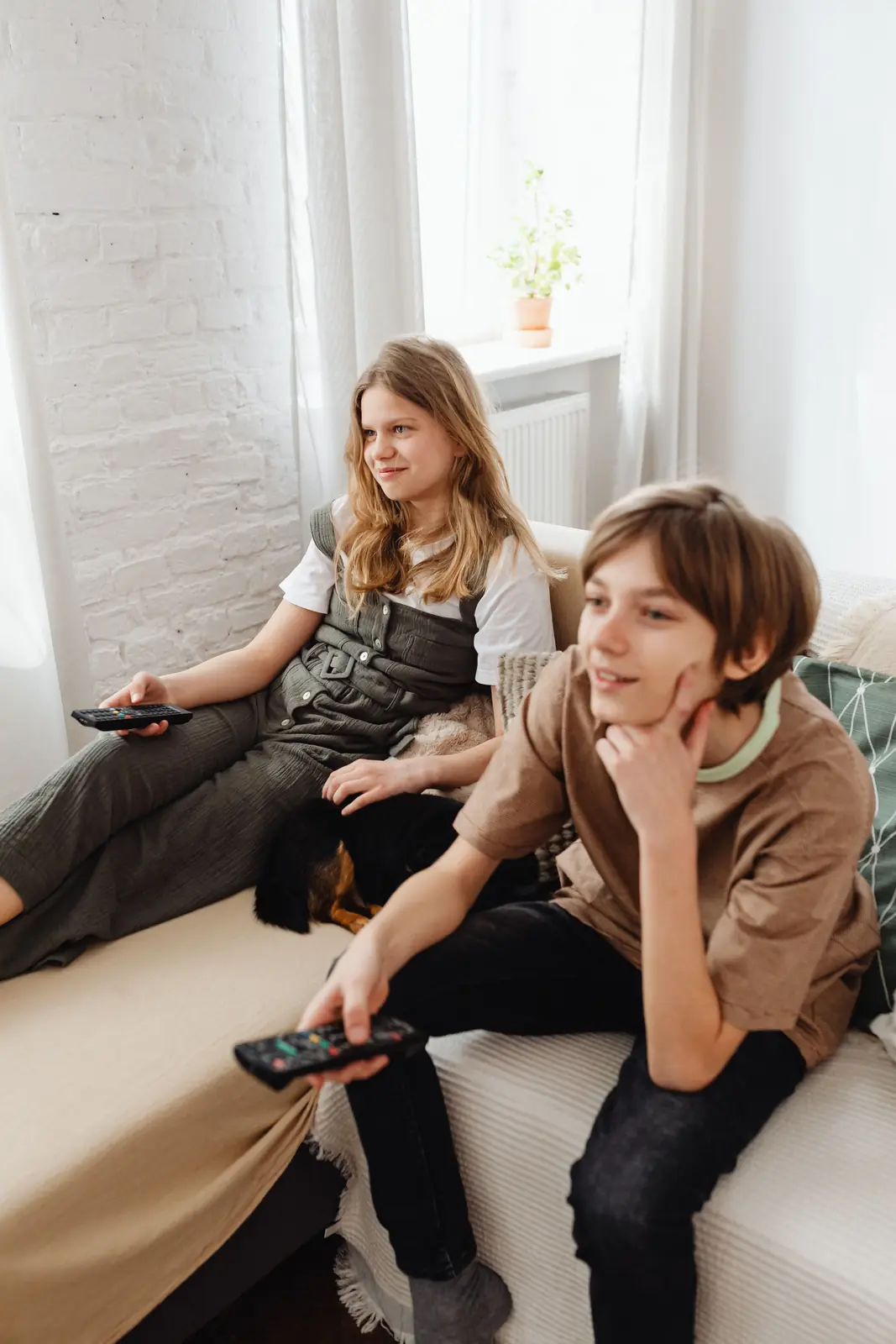 Two teenagers watching TV on a sofa in a living room